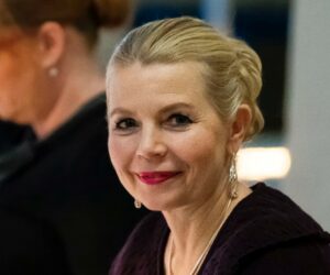 Vaalea nainen katsoo kameraa.