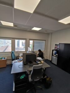 Toimistohuone, jossa yksi henkilö pöydän ääressä.