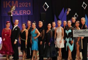 Tanssipareja seisoo rivissä latinalaistanssiasuissa.